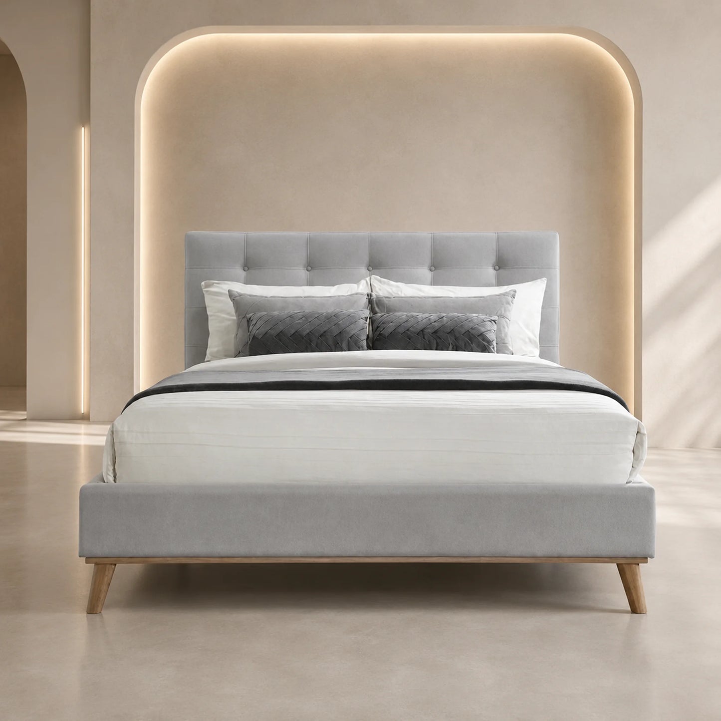 A modern upholstered bed with a light gray tufted headboard and matching footboard, styled with white and gray bedding in a minimalist beige bedroom with warm ambient lighting.