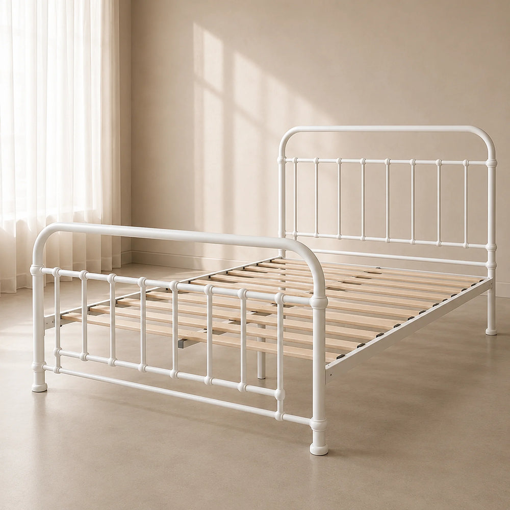 A white metal bed frame with wooden slats, shown in a softly lit beige room with curtains and sunlight streaming in.