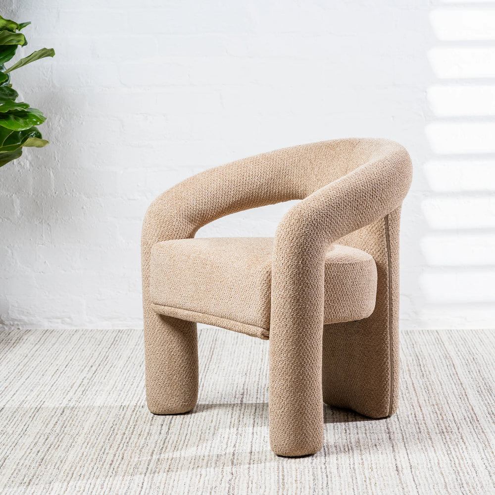 A modern low-profile armchair upholstered in a textured beige bouclé fabric