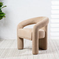 A modern low-profile armchair upholstered in a textured beige bouclé fabric