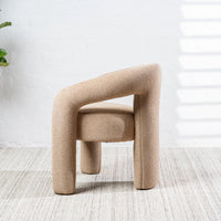 A modern upholstered accent chair with a chunky curved backrest and cylindrical legs, upholstered in a textured beige fabric