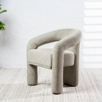 A modern low-profile armchair upholstered in a textured light beige fabric