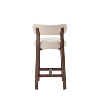 A modern bar stool with a curved backrest and seat cushion upholstered in a light beige textured fabric, supported by a dark brown wooden frame with a footrest, shown against a plain white background.