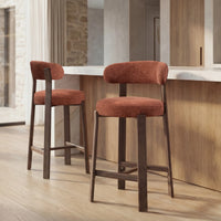 Two bar stools with rust-orange upholstered seats and backs on dark wood legs