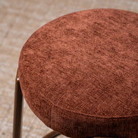 Close-up of a round upholstered stool seat in a textured rust-brown fabric