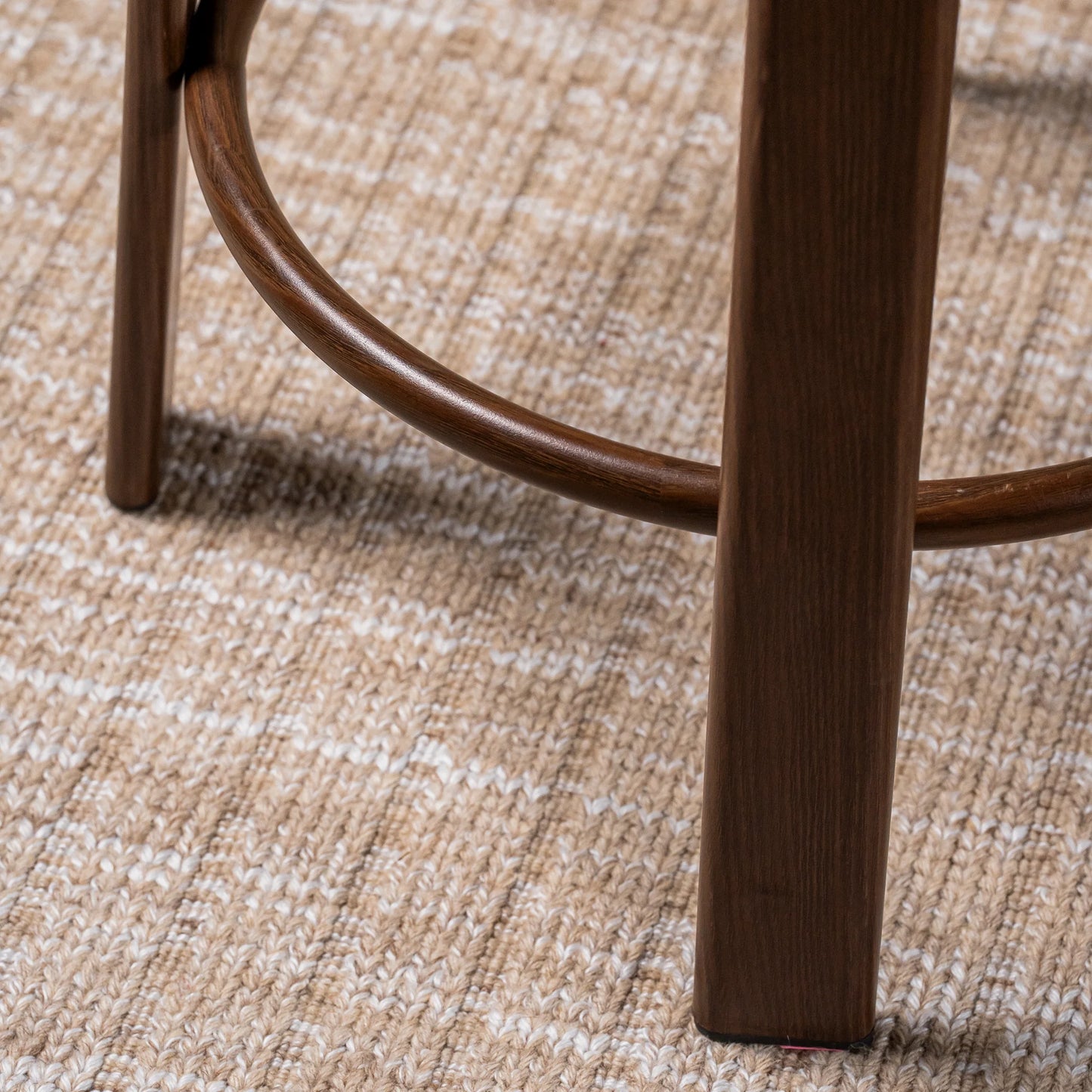 Close-up of a wooden stool leg and curved footrest