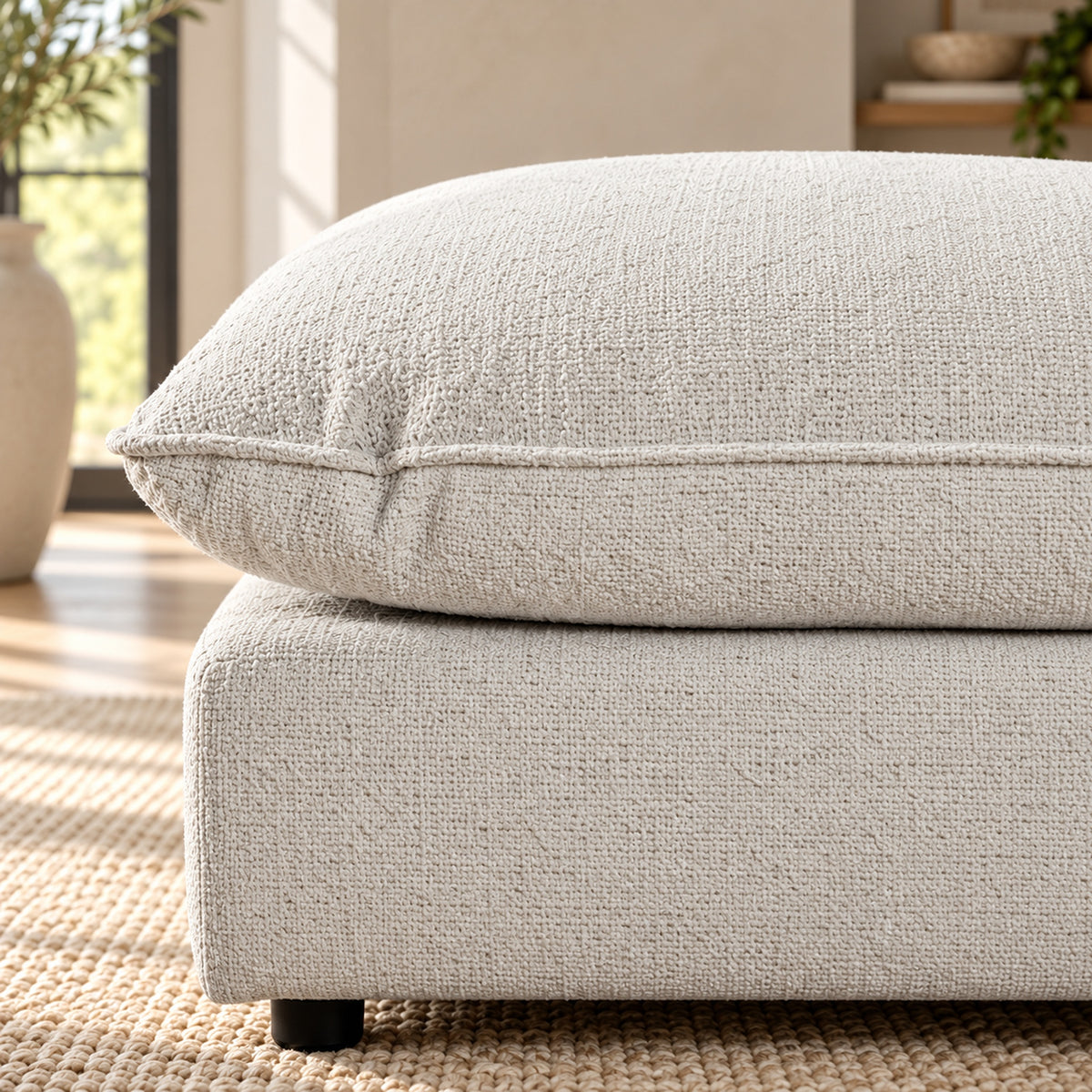 Bradman Snow duck feather ottoman with plush square cushion and textured Shay fabric upholstery, close up view