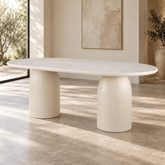Calisto Pebble oval dining table with micro-cement finish and two cylindrical pedestal bases, angled front view