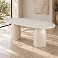 Calisto Pebble oval dining table with micro-cement finish and two cylindrical pedestal bases, angled front view
