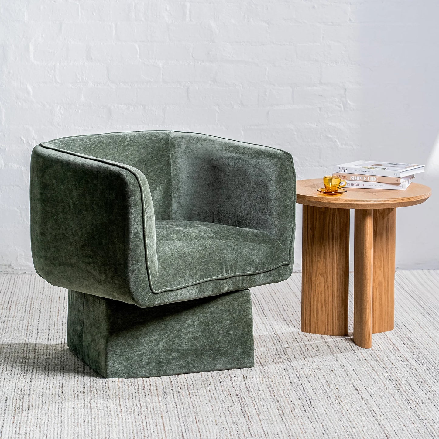 A modern barrel-style armchair upholstered in textured sage green velvet