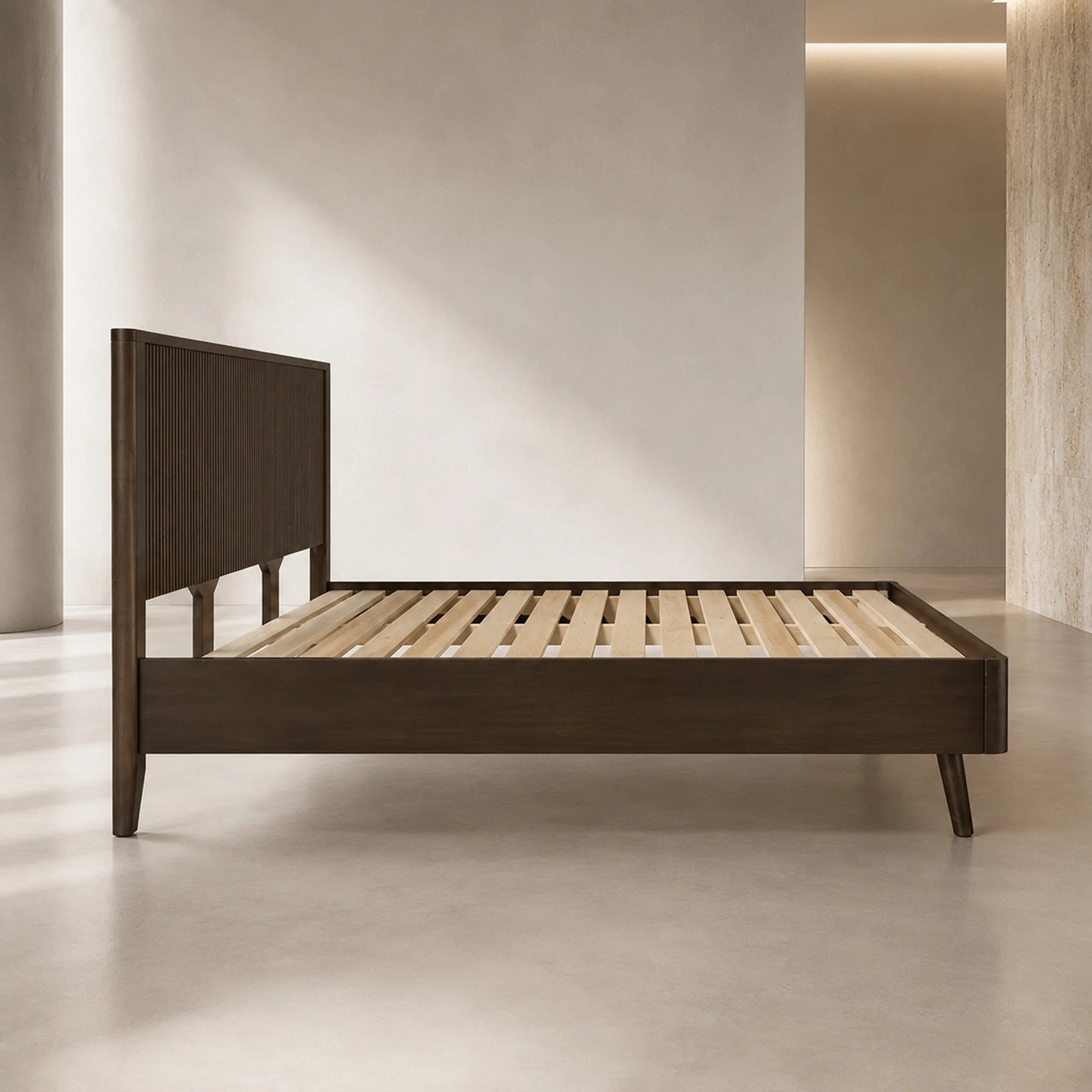 A modern dark brown wooden bed frame with a slatted platform base and a tall, ribbed headboard, shown in a minimalist, warm-toned bedroom setting.