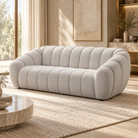 Kenya Beige 3 seater sofa with curved low-profile design, slanted arms and vertical panel detailing, angled view