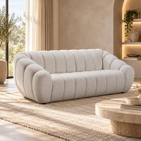 Kenya Beige 3 seater sofa with curved low-profile design, slanted arms and vertical panel detailing, angled view