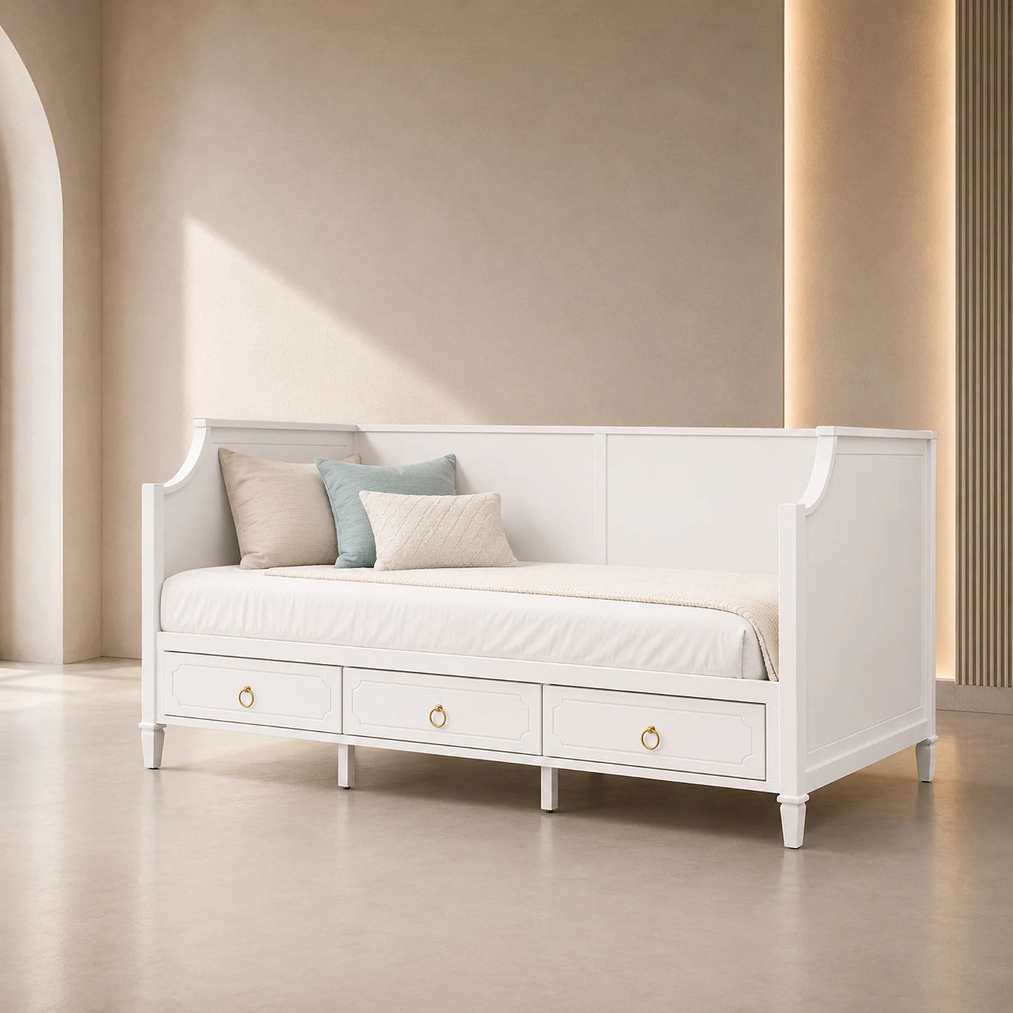 A white wooden daybed with three storage drawers underneath, styled with white and light blue pillows in a minimalist beige room.