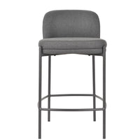 A modern bar stool with a gray upholstered seat and curved backrest, supported by a slim dark metal frame with a footrest.
