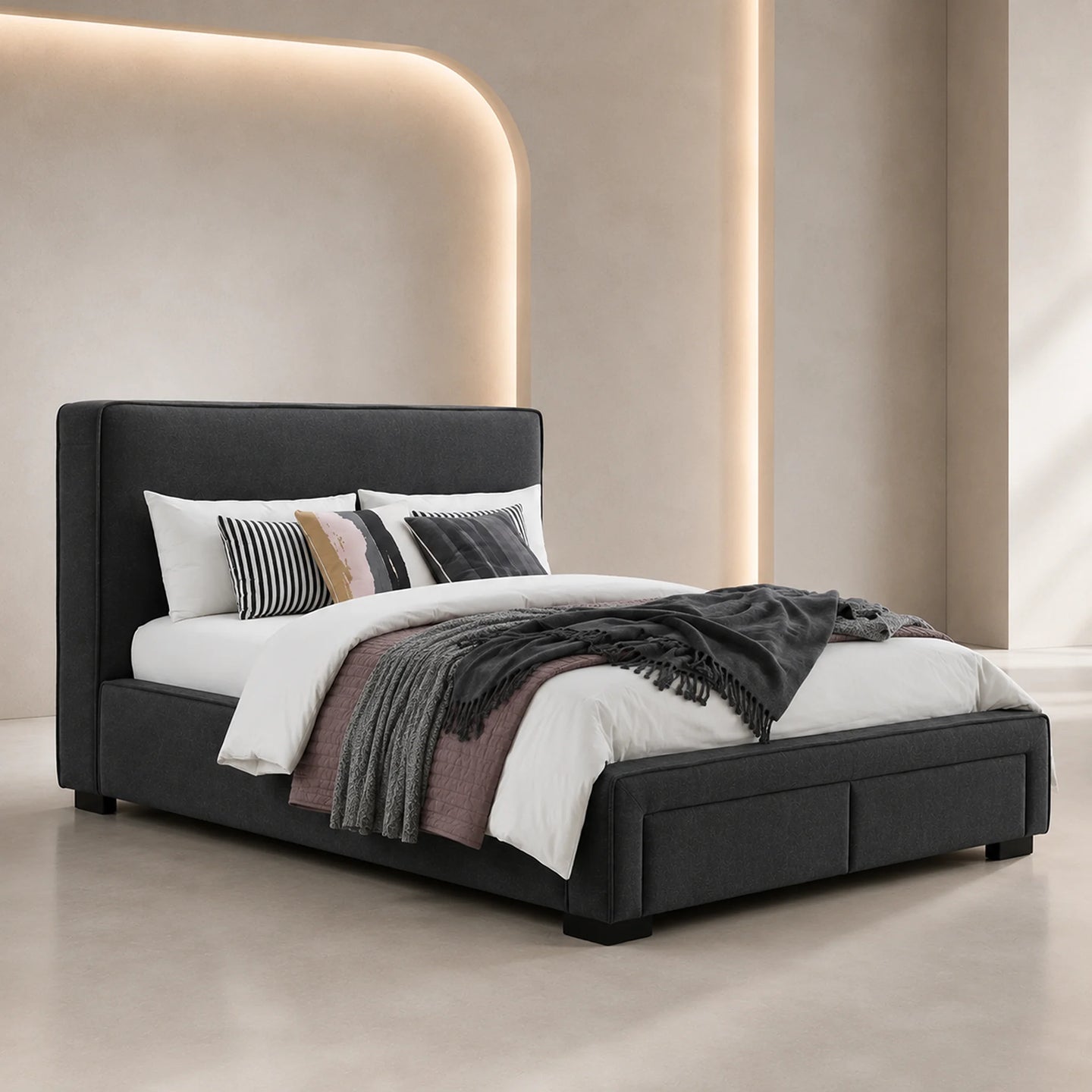 A modern upholstered bed frame in dark charcoal gray, styled with white bedding, striped pillows, and a dark throw blanket in a minimalist beige bedroom setting.