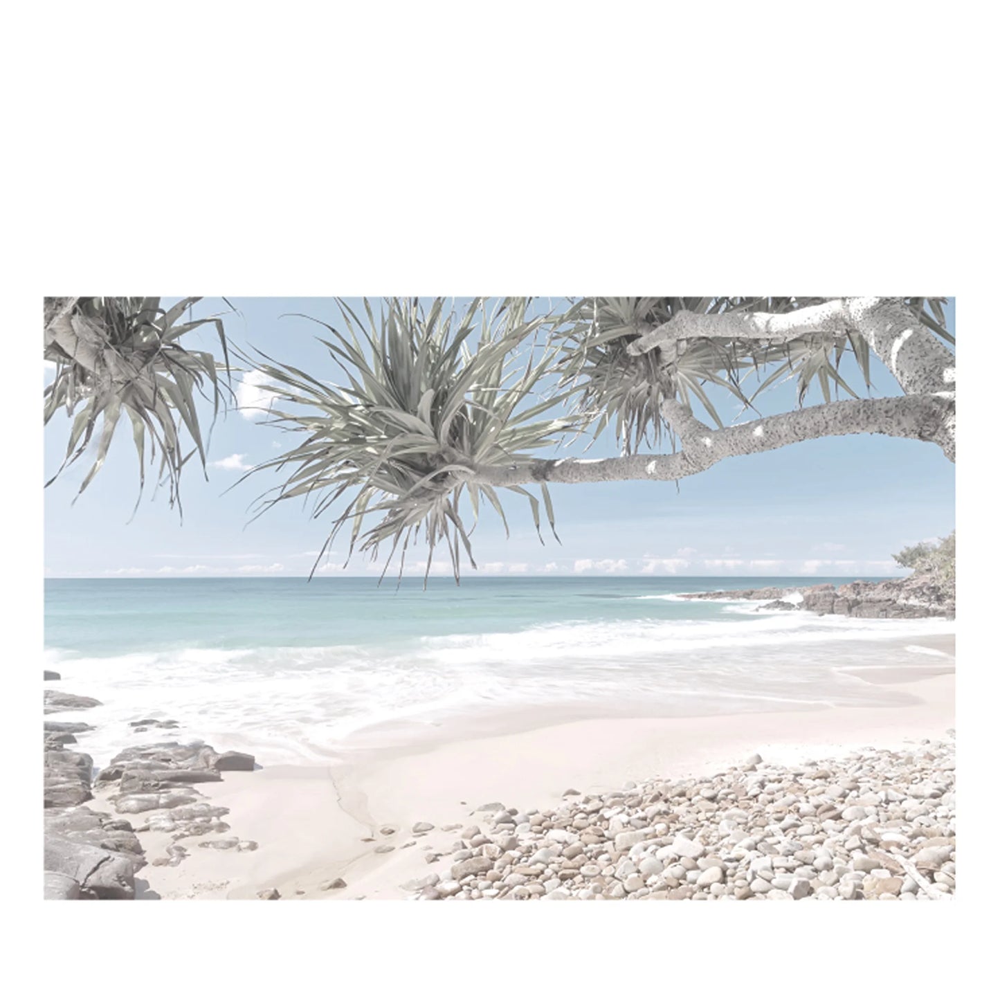 A coastal beach scene with pale sand, pebbles, turquoise water, and a pale blue sky, framed by overhanging leafy branches in the foreground.