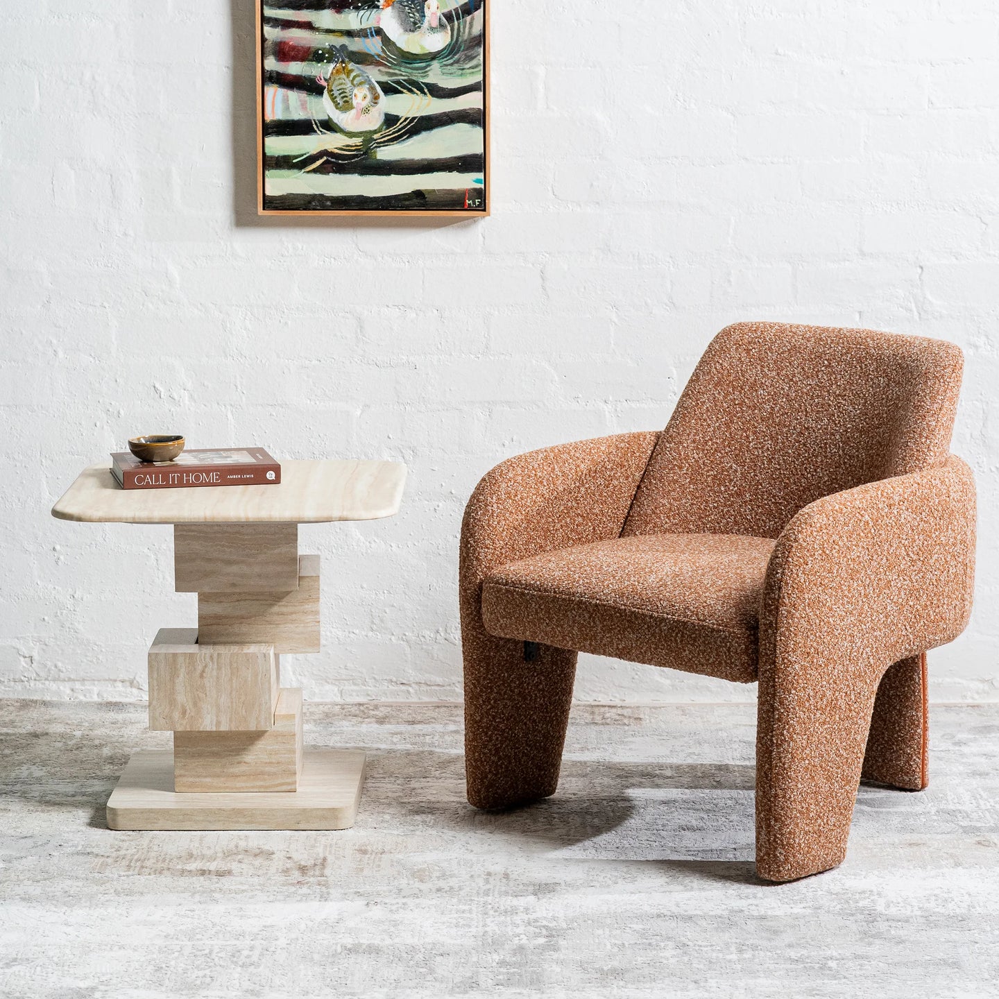 A mid-century modern armchair upholstered in a textured brown bouclé fabric