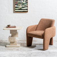 A mid-century modern armchair upholstered in a textured brown bouclé fabric