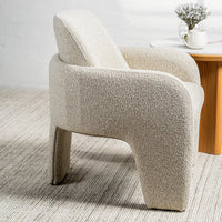 A modern sculptural armchair upholstered in a textured bouclé fabric in a light oatmeal beige color